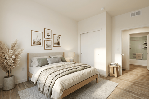 A bedroom with a large bed and a potted plant.