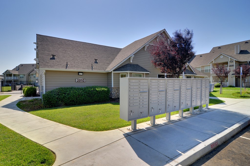 a mailbox sits on the side of a sidewalk in front of a house