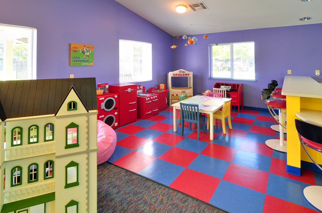 a childs play area with a large dollhouse table and chairs