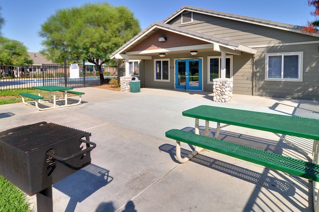 a picnic table and grill are in front of a building with a blue door