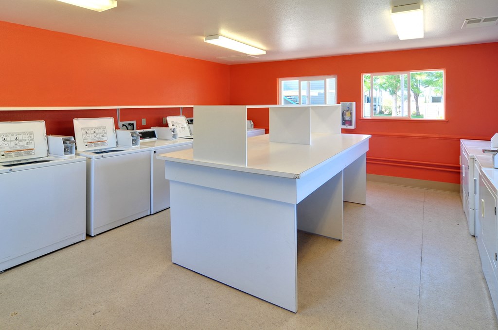 a laundry room with white washers and dryers and orange walls