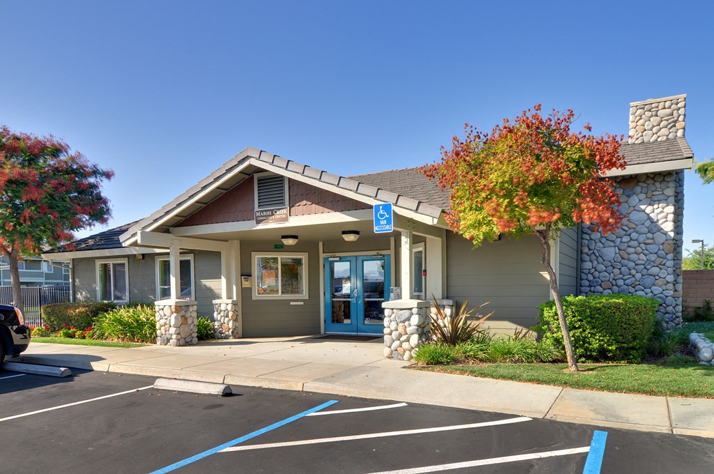 a grey building with a blue door and a tree with red leaves in front of it