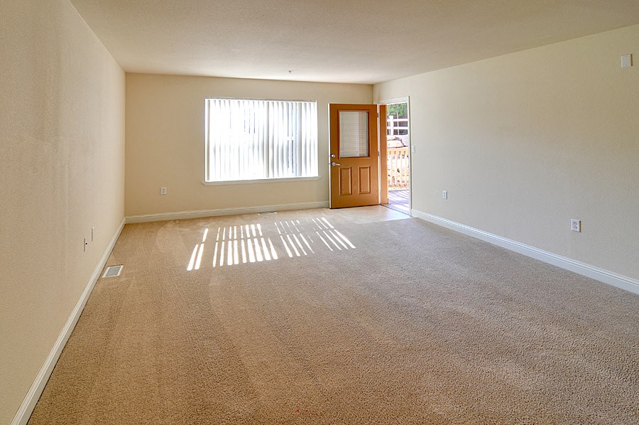 an empty living room with a door and a window