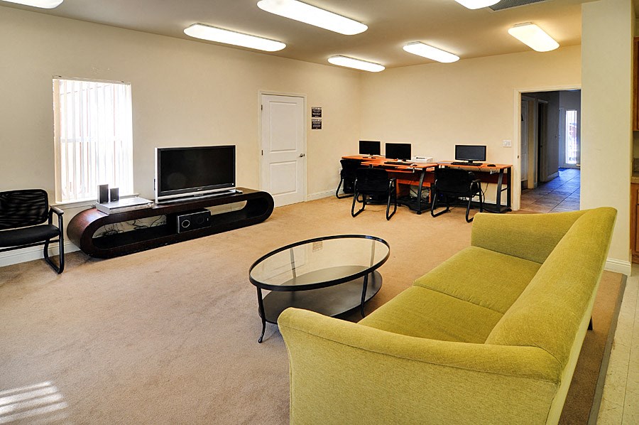 a living room with a couch and a table with computers on it