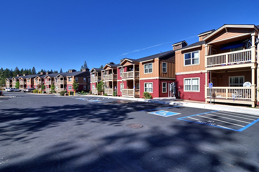 an empty parking lot in front of a row of apartment buildings