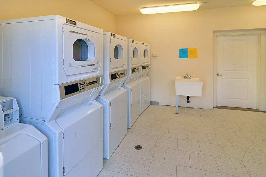 a laundry room with four washers and dryers and a sink