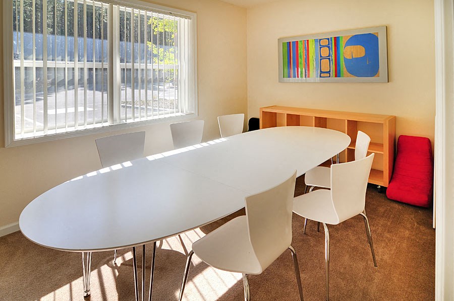 a conference room with a white table and chairs and a window