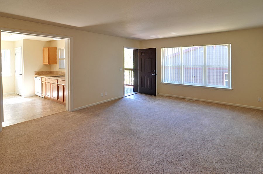 an empty living room and kitchen with a large window