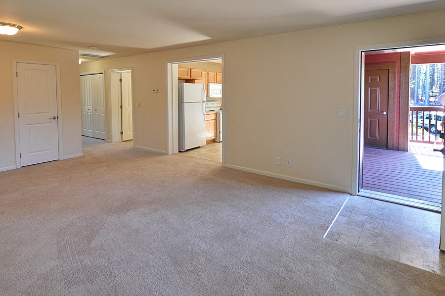 an empty living room and kitchen with a door to a balcony