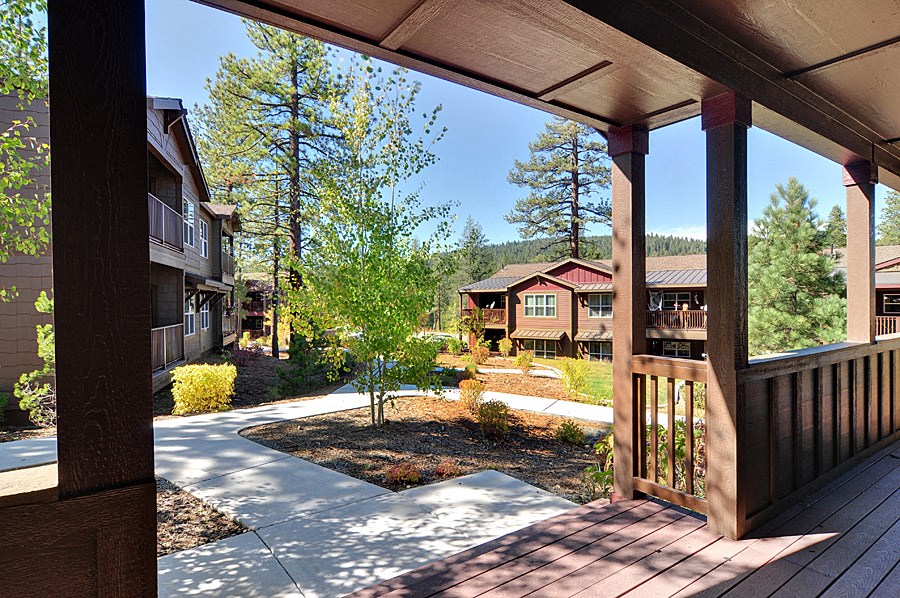 a covered porch with a view of houses and trees
