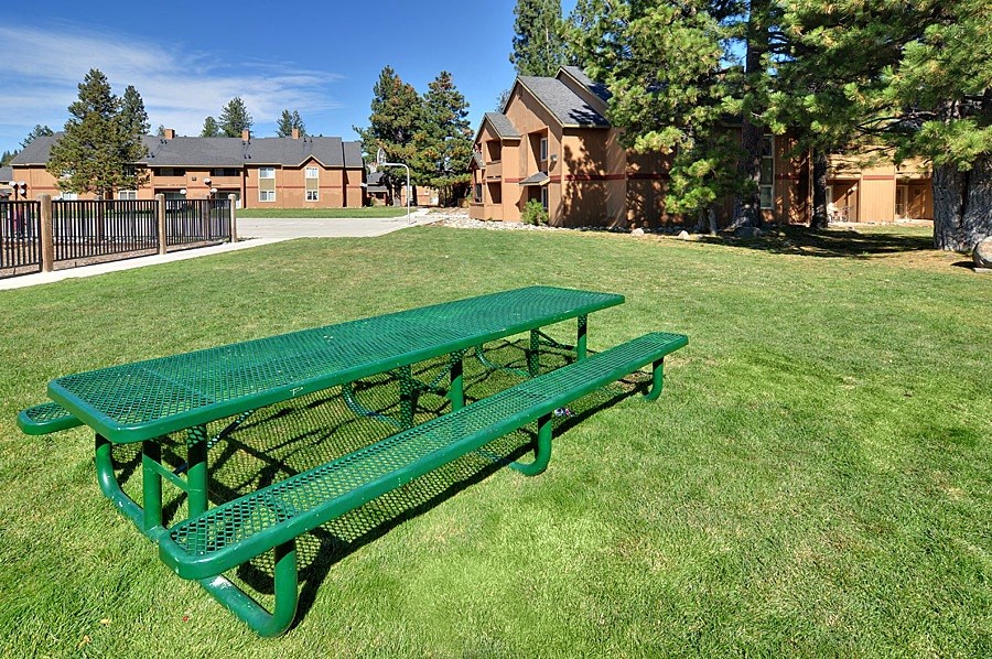 a green picnic table in a park with houses in the background