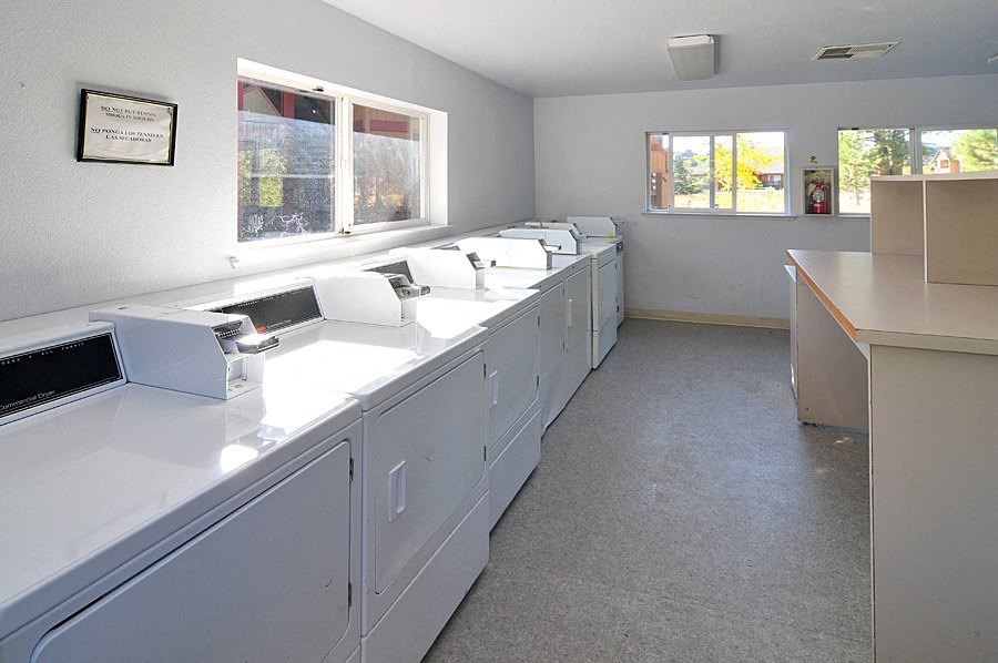 a laundry room with four sinks and two windows