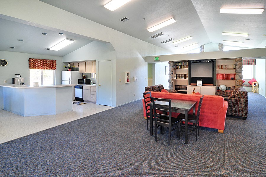 a room with a table and chairs and a kitchen in the background