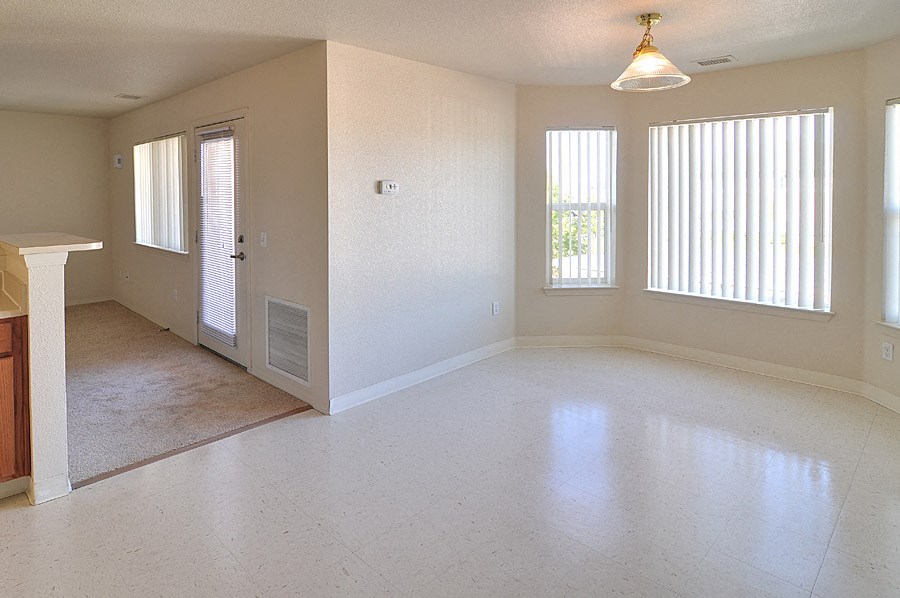 the living room of an empty house with a white floor and windows