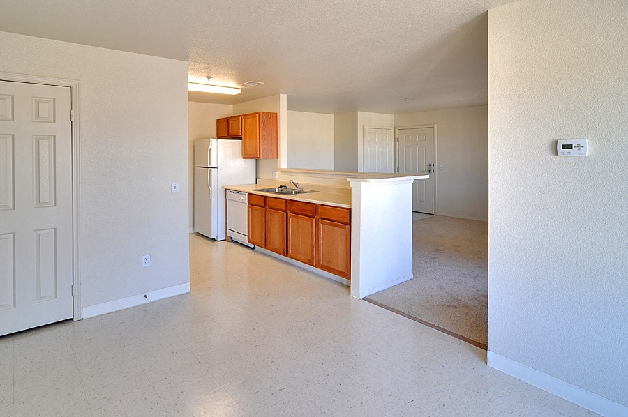 an empty kitchen with white appliances and wooden cabinets