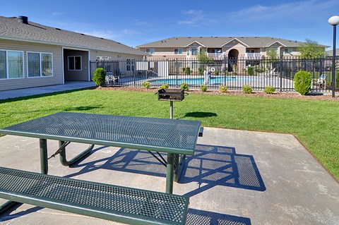 a picnic table with a grill in a yard with a pool