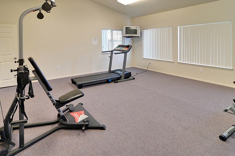 an exercise room with exercise equipment and a tv