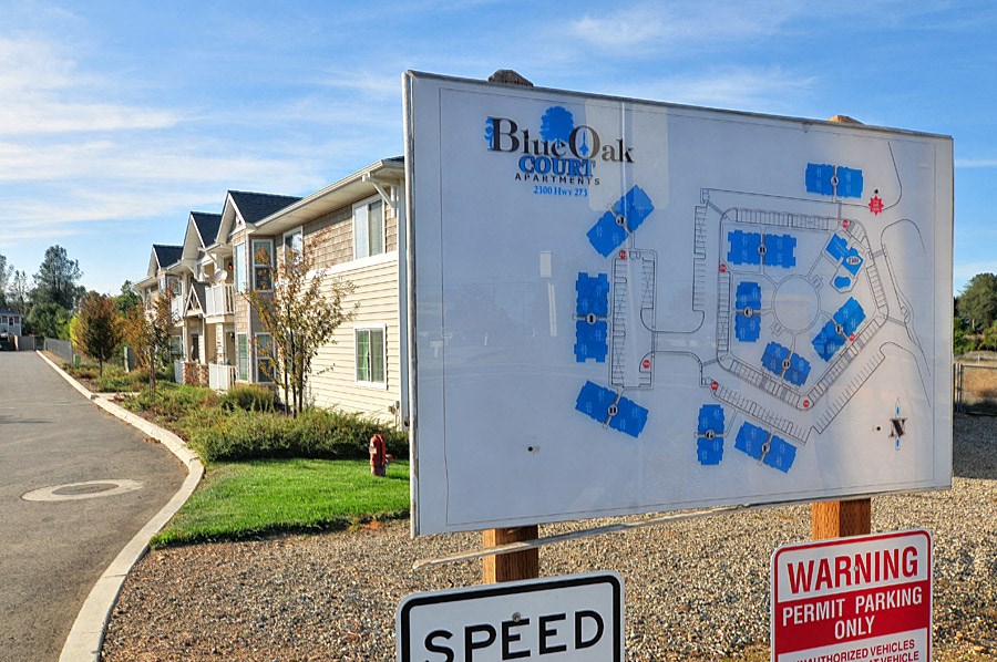 a sign in front of an apartment complex with a speed limit sign in the foreground