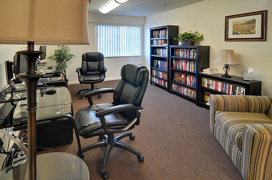 a living room with chairs and a table and a book shelf