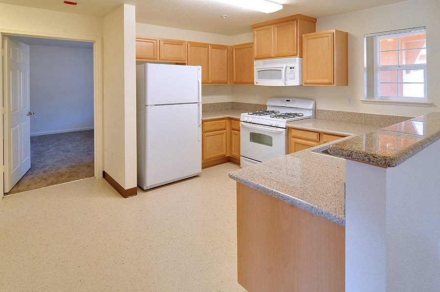 an empty kitchen with white appliances and granite counter tops