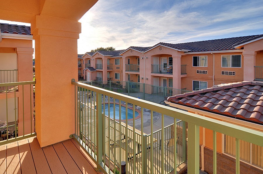 a balcony with a pool and apartments in the background