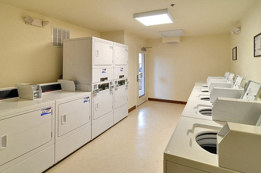a kitchen with white appliances and a row of washers and dryers