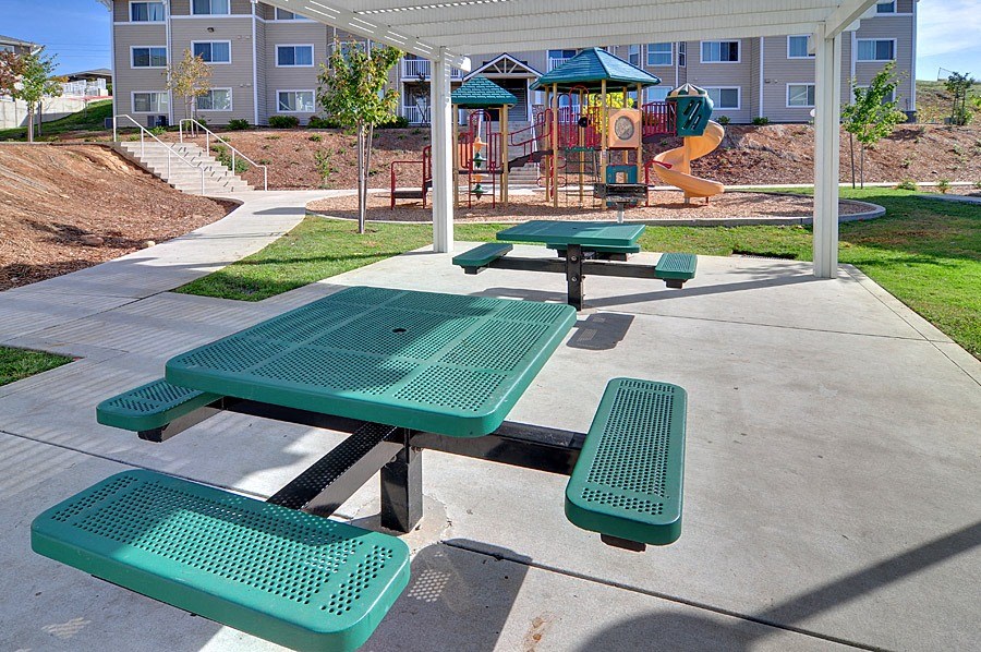 a picnic area with benches in front of a playground