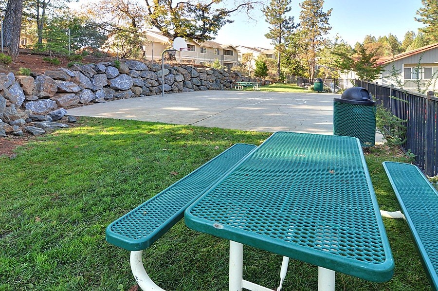 a green picnic table sits in front of a basketball court