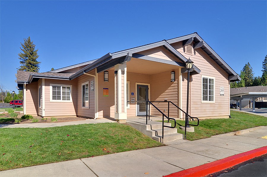 the front of a small brown house with stairs and a sidewalk