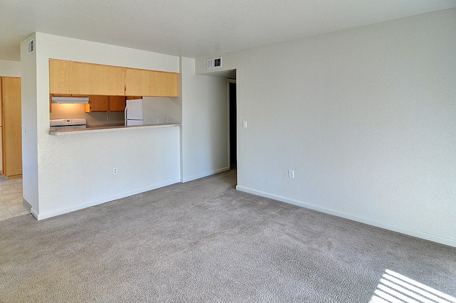 the living room and kitchen of an empty apartment