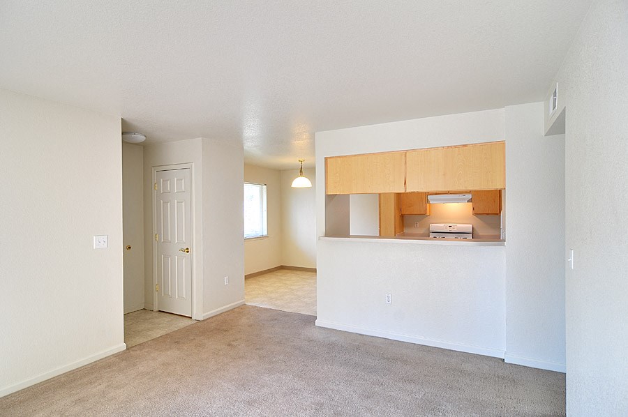 an empty living room and kitchen with a door to the bathroom