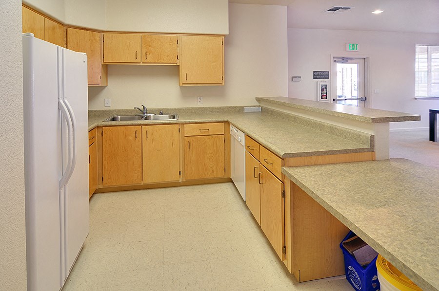 an empty kitchen with wooden cabinets and a refrigerator