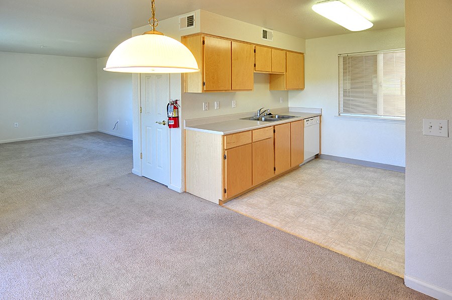 an empty kitchen with wood cabinets and a white counter top
