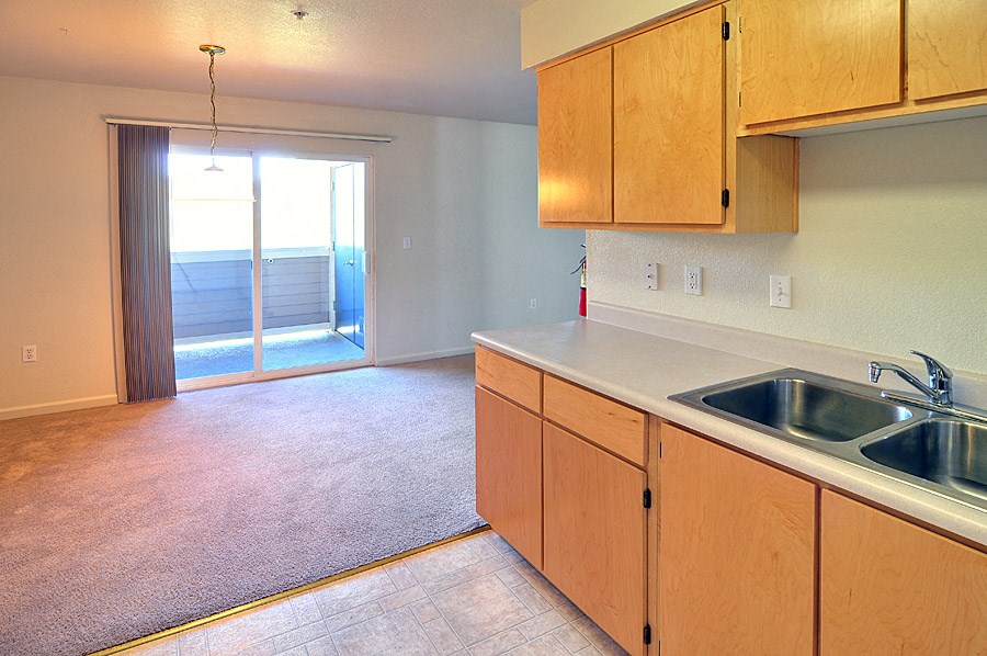 a kitchen and living room with a sliding glass door to a balcony