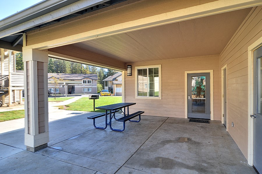 a covered patio with a picnic table and a door
