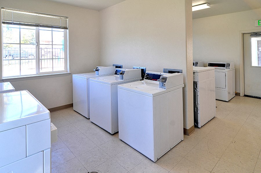 a group of washers and dryers in an empty laundry room