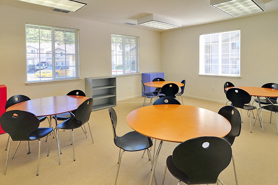 a common room with tables and chairs and windows