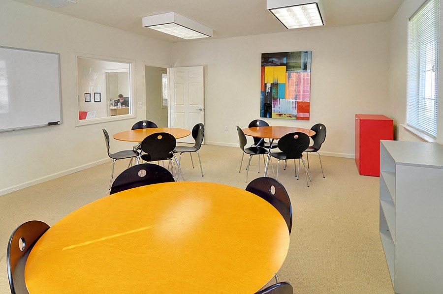 a conference room with tables and chairs and a whiteboard