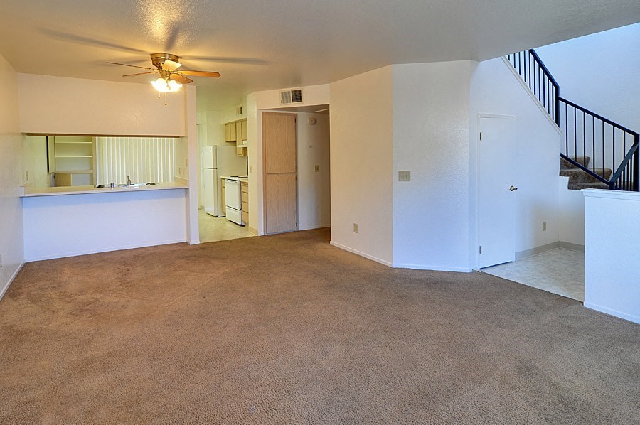 an empty living room with a ceiling fan