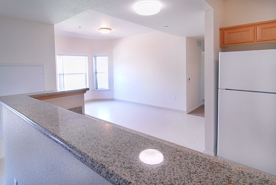 an empty kitchen with a granite counter top and a refrigerator