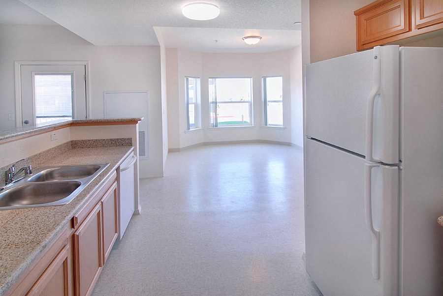 an empty kitchen with a refrigerator and a sink