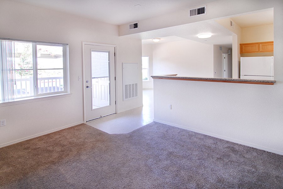 an empty living room and kitchen with a door to a balcony