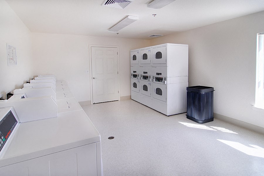 an empty kitchen with white appliances and counters and a door