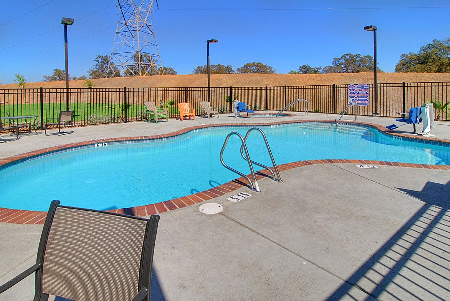 a swimming pool with chairs and a fence around it