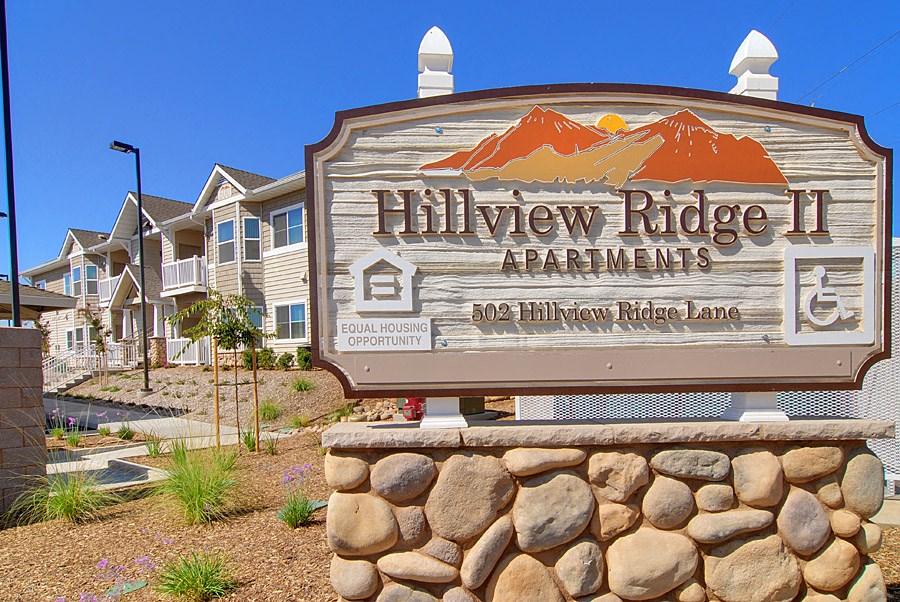 a sign for hillview ridge apartments with mountains in the background