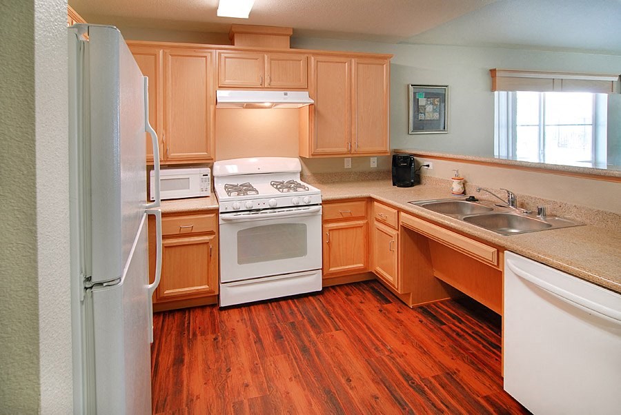 a kitchen with wooden floors and white appliances