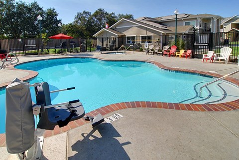 a swimming pool with chairs and a house in the background