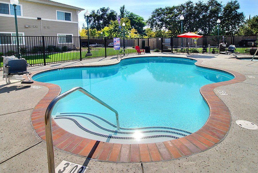 a pool with a fence and chairs around it