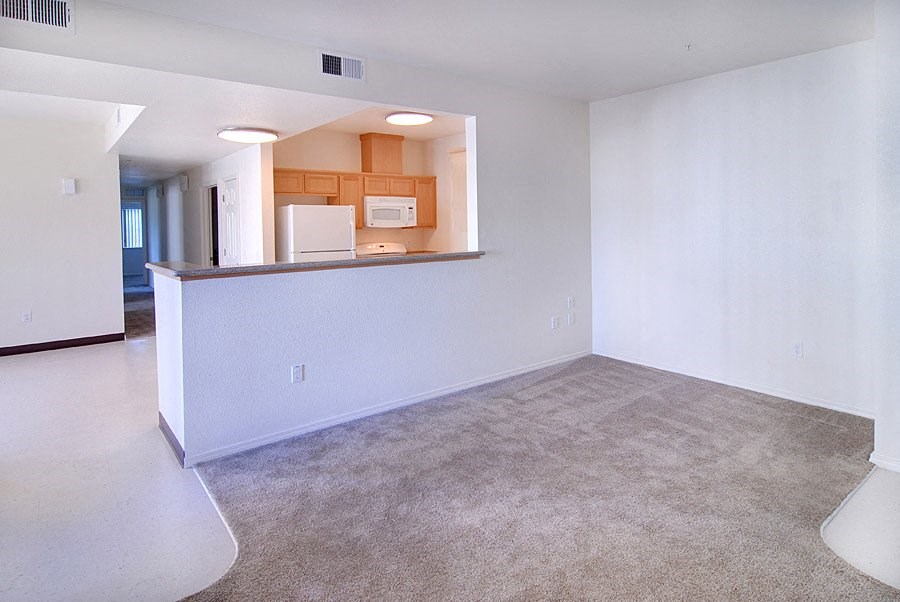 an empty living room with a kitchen in it