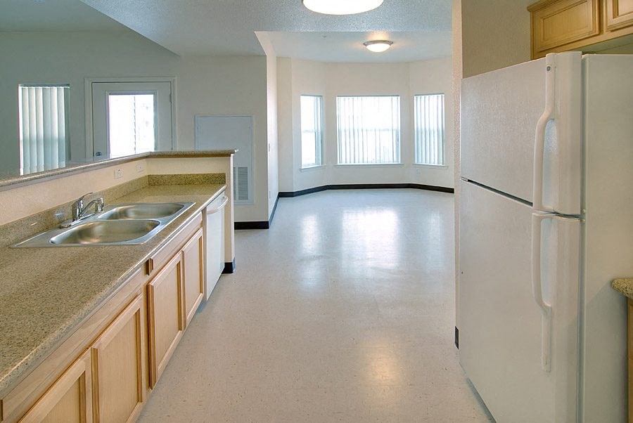 an empty kitchen with a refrigerator and a sink